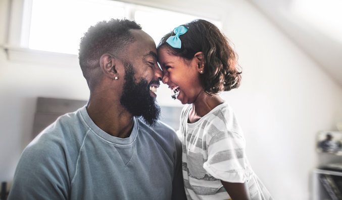 father and daughter laughing in bedroom